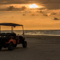 Golf cart parked on beach near sunset in Port Aransas, Texas