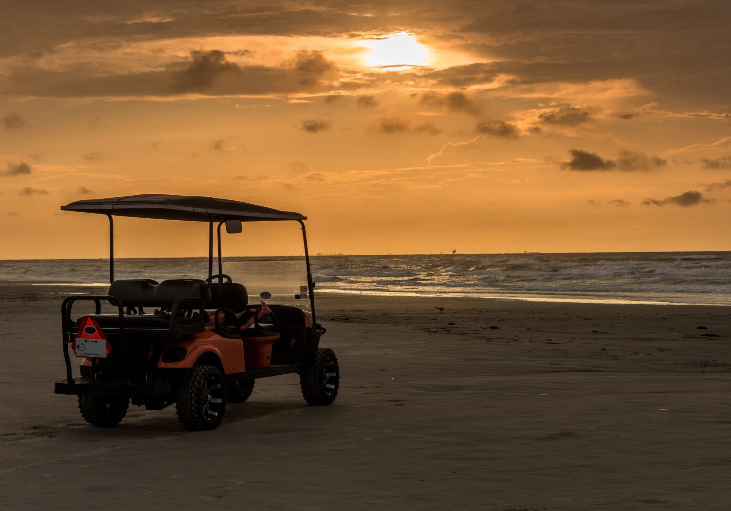 Golf cart parked on beach near sunset in Port Aransas, Texas