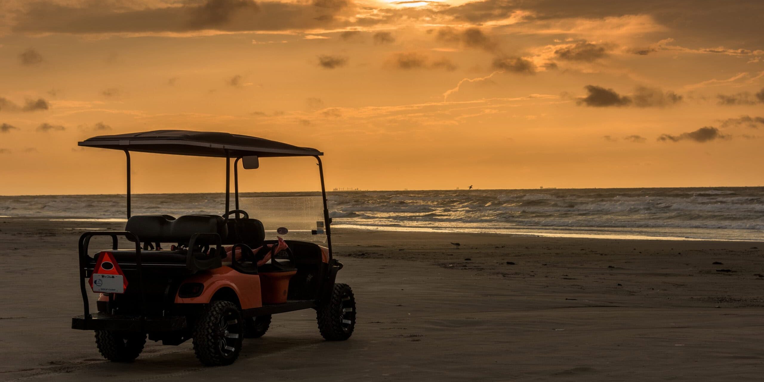 Golf cart parked on beach near sunset in Port Aransas, Texas